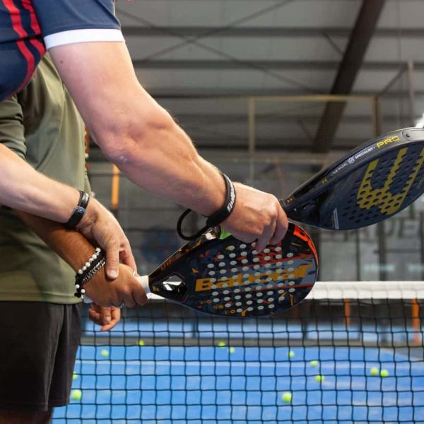 Padelspelers met rackets op indoor padelbaan tijdens toernooi.