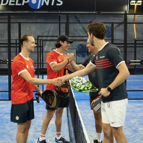 Vrienden die elkaar de hand schudden op padelbaan.